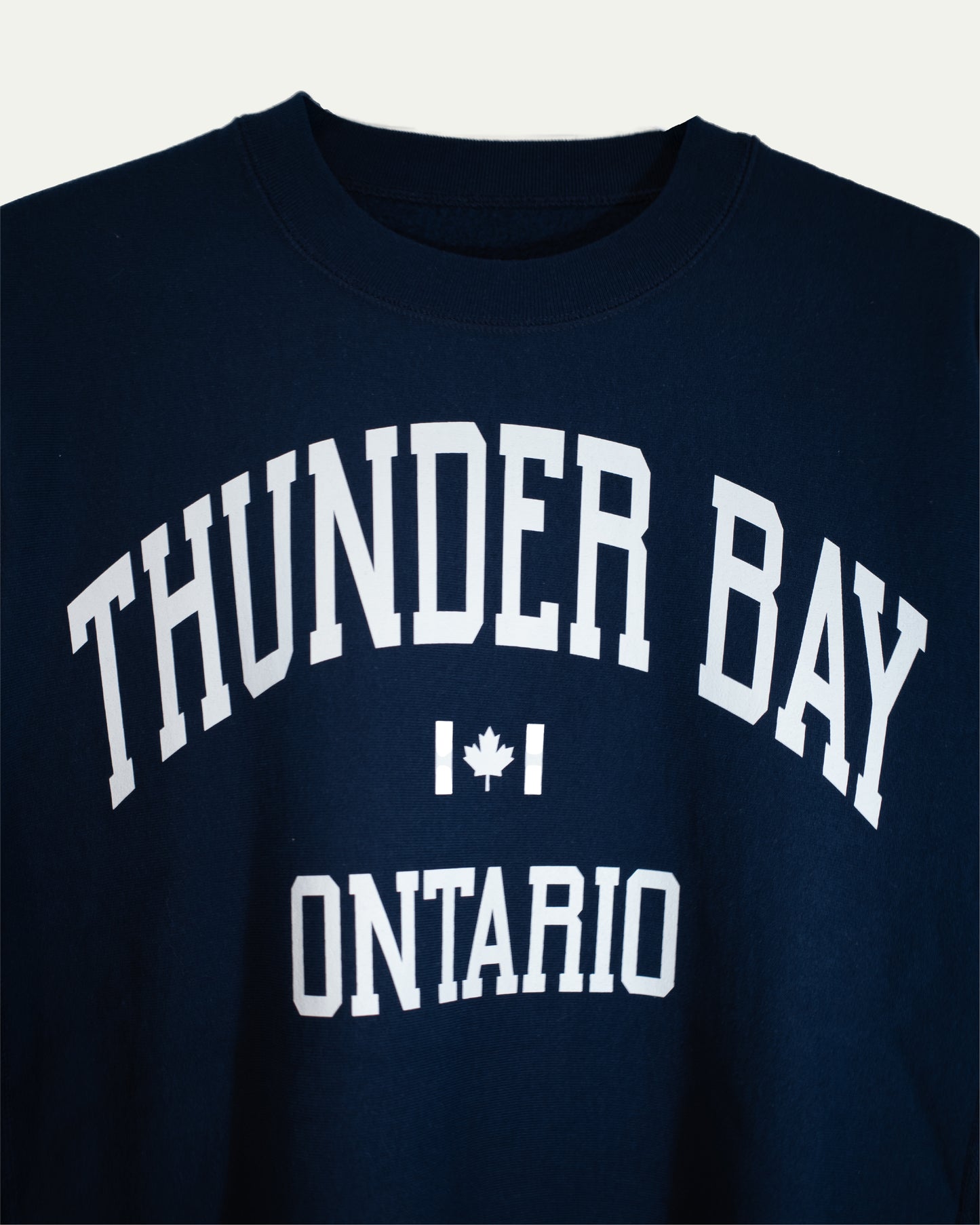 Navy blue sweatshirt with 'Thunder Bay Ontario' text and a maple leaf on a white background