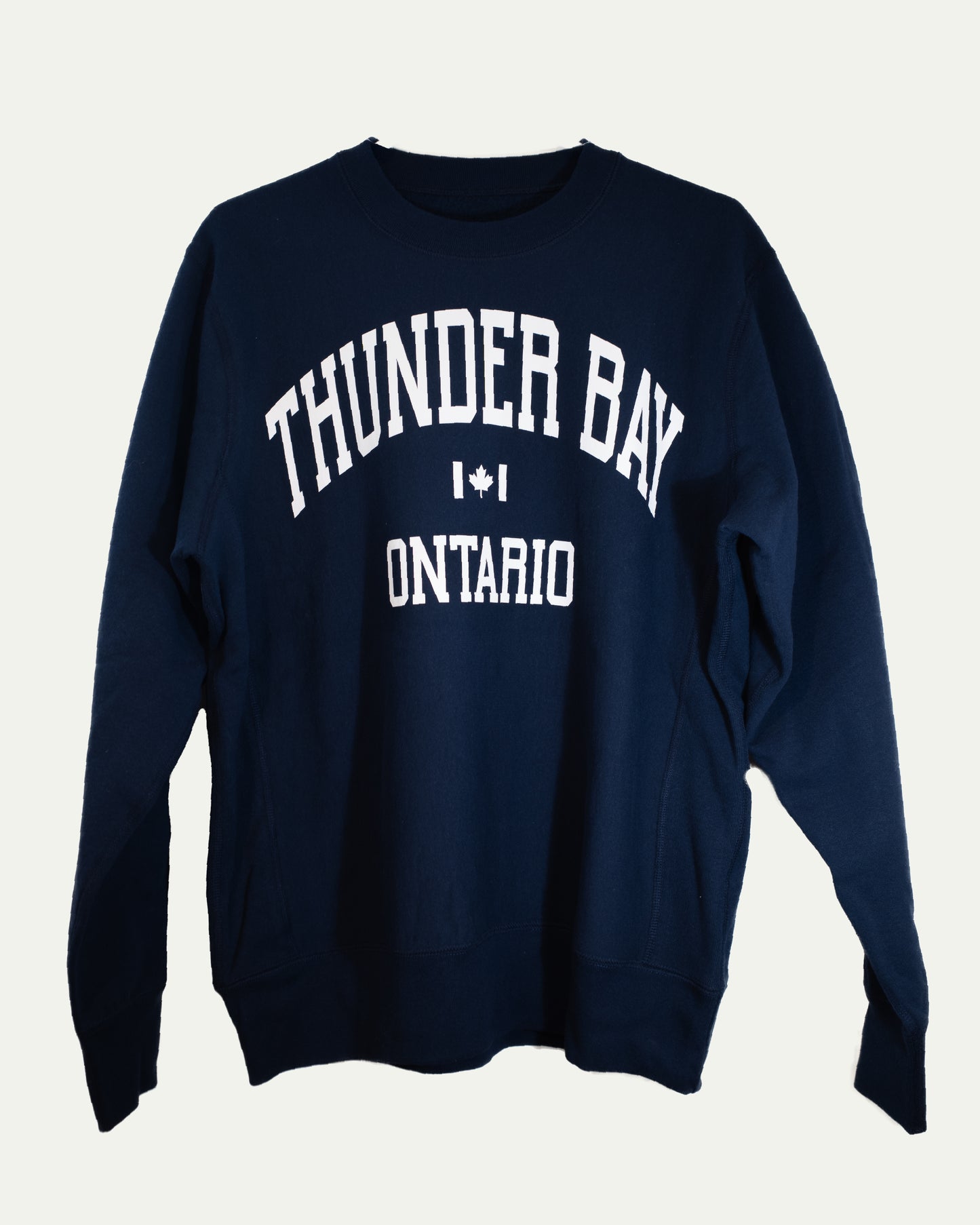 Navy blue sweatshirt with 'Thunder Bay, Ontario' text on a light gray background